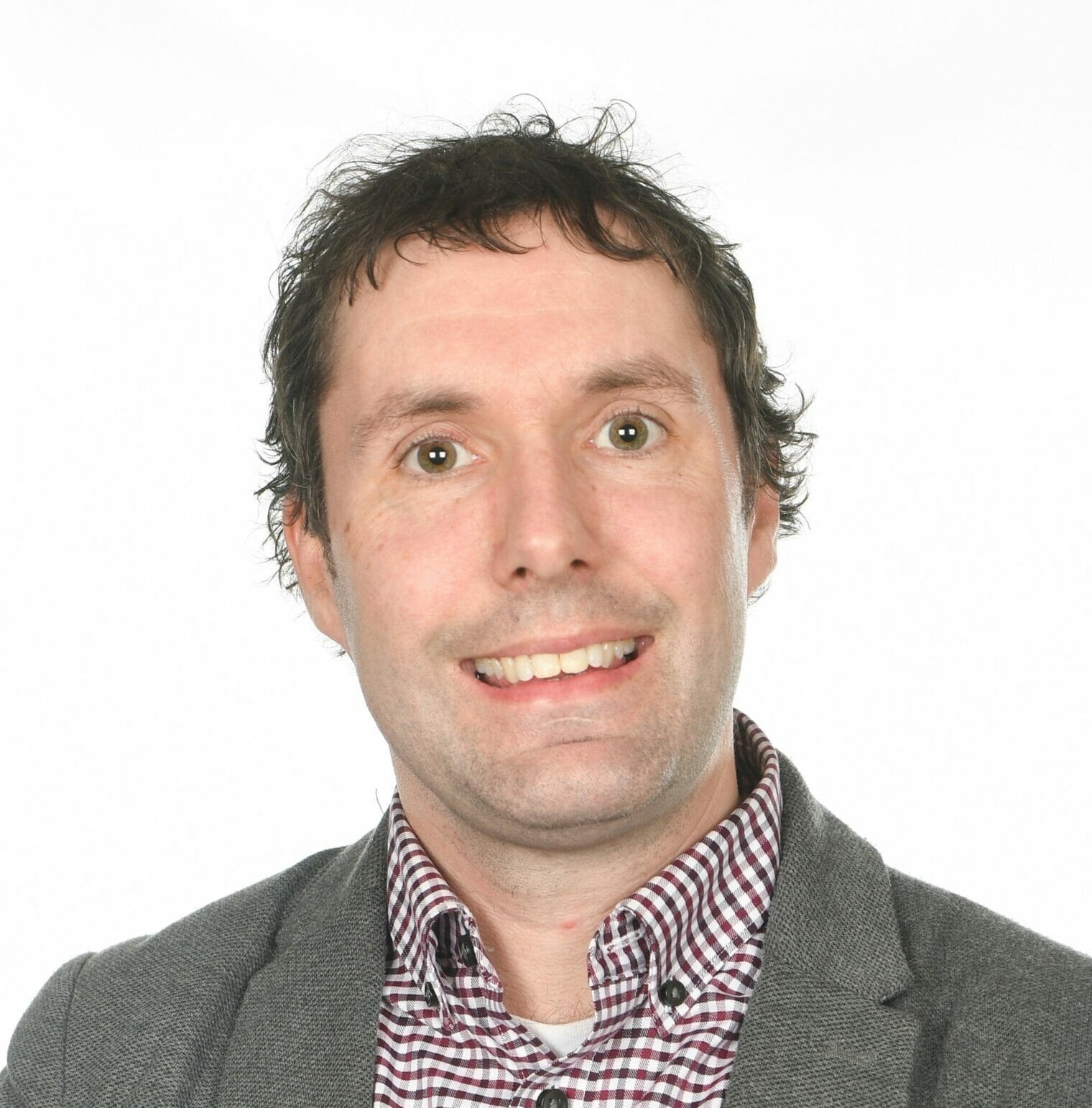 Impact Fellowship | curaJOY A man in a grey jacket and plaid shirt is smiling, radiating families' emotional wellness.